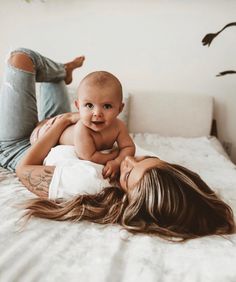 two women laying on top of a bed with a baby in their lap and one holding the other