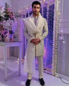 a man standing in front of a purple and white backdrop wearing a tuxedo