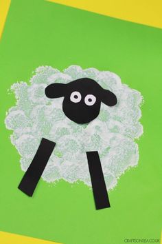 a sheep made out of paper sitting on top of a green surface