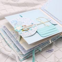 a close up of an open book on a bed with white sheets and blue paper