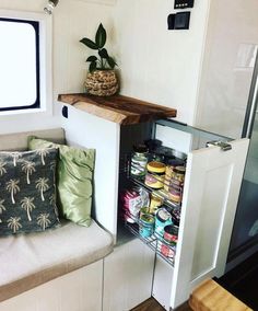 an open cabinet in the corner of a small room with pillows and other items on it