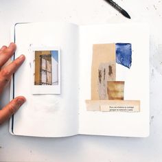 a hand holding an open book with pictures on it and a pen next to it