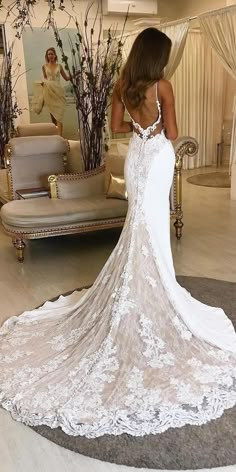 a woman in a white wedding dress looking down at the back of her bridal gown