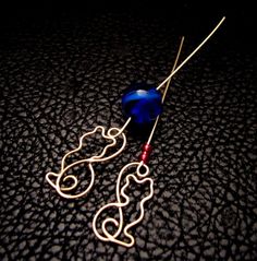 a blue bead and some wire on a black surface with a red ball in the middle