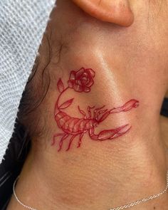 a woman with a scorpion tattoo on her neck and behind the neck is a rose