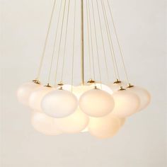 a chandelier with five white balls hanging from it's center and four gold poles