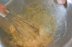 someone mixing batter in a metal bowl with a whisk