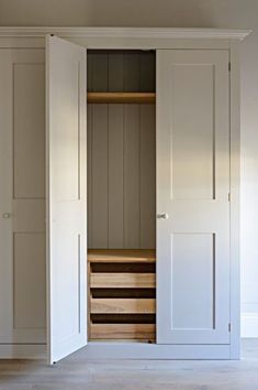 an open closet with wooden drawers and white doors in a room that has light wood flooring