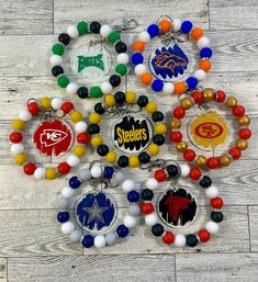 several nfl bracelets are displayed on a wooden floor with beads and balls around them