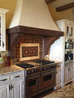 a stove top oven sitting inside of a kitchen next to white cupboards and counter tops