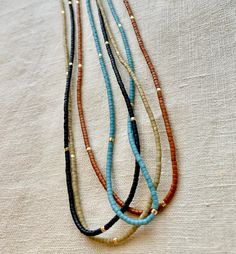 Great for everyday wear! Very tiny and delicate. Muted neutral tones. This tiny necklace is made with high quality Japanese seed beads that are perfect cylinders. Gold-filled clasp. Natural silk cord with frayed tassel ends. Available in 4 matte colors: burnt umber, palm, black, and ocean. 📏Not sure which length to choose? Add a chain extender: https://etsy.me/34lPf3m 🌎 Packaging 🌎 To be environmentally responsible about packaging we will package orders together in the same box. If certain it Adjustable Gold Beaded Everyday Necklaces, Adjustable Gold Beaded Necklaces For Everyday, Brown Beaded Necklaces With Tiny Beads, Brown Beaded Necklace With Tiny Round Beads, Minimalist Adjustable Beaded Necklace With Gold Beads, Everyday Gold Beaded Necklaces, Minimalist Gold Beaded Necklace For Everyday, Everyday Beaded Necklace With Round Beads, Everyday Bohemian Beaded Necklaces With Tiny Beads