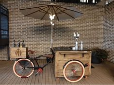 an old fashioned bicycle is parked next to a cart with drinks on it and an umbrella