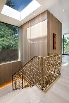 a wooden stair case in front of a window with skylight above it and wood paneling on the walls