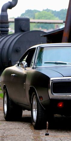 an old muscle car parked in front of a train