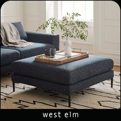 a living room scene with focus on the ottoman and coffee table in front of the couch