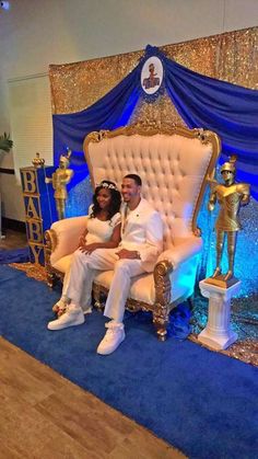 a man and woman sitting on a chair in front of a stage with blue lights