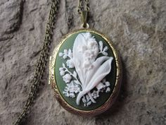 "Beautiful cameo lockets The cameo is a gorgeous lily of the valley. Stunning colors, I have these in so many pretty colors and finishes, as well as in barrettes, necklaces, brooches and so much more to complete the look. The bronze and silver plated lockets are Victorian style with beautiful etching on both the front and back about 2\" long. They can hold two photos or a treasured keepsake. Pass down from generation to generation The bronze locket includes a 24\" rolo link chain with a lobster Vintage White Jewelry For Ceremonial Occasions, White Engraved Wedding Jewelry, White Engraved Jewelry For Wedding, Victorian White Wedding Jewelry, Antique Flower Necklaces For Weddings, White Victorian Jewelry For Ceremonial Occasion, White Heirloom Necklace For Wedding, Heirloom White Necklace For Wedding, Heirloom White Wedding Necklaces