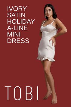 a woman in a white dress is standing with her hands on her hips and the words ivory satin holiday a - line mini dress