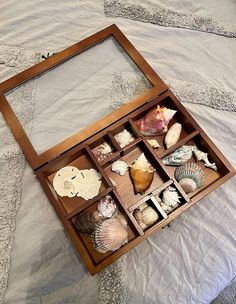 a wooden box filled with shells on top of a bed