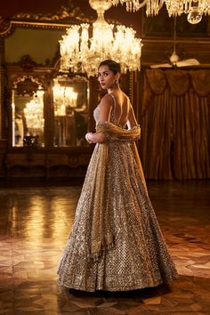 This antique gold lehenga set features intricate embroidered in sequin & crystal work The matching blouse shows tassels at the waist and t is paired with a matching net dupatta with border and tassels on all four sides.From Seema Gujral's Falaknuma collection. DELIVERY TIMEPlease allow 8-12 weeks for your outfit to arrive. FABRIC DETAILSNet Professional cleaning only. Gold Floor-length Anarkali Set With Sheer Dupatta, Floor-length Sheer Gold Dupatta, Gold Sequined Traditional Sharara, Traditional Drape Gold Sharara With Sequins, Gold Embellished Lehenga For Reception, Traditional Drape Sequin Gown For Navratri, Gold Sharara With Sequins And Traditional Drape, Gold Sharara With Sequins In Traditional Drape, Designer Gold Gown With Sheer Dupatta