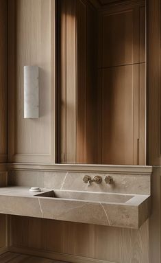 a bathroom sink sitting under a mirror next to a wall mounted faucet in front of a wooden cabinet