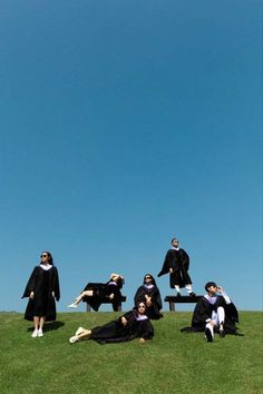 several people in graduation gowns are sitting on a bench and posing for the camera