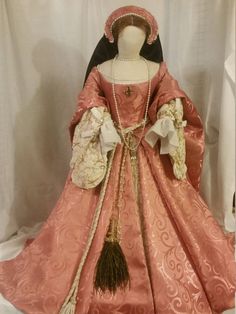 This is a Fashion Doll of Princess at age 13 to 15 in a beautiful coral pink gown.  She is 3 feet tall and 3 feet wide at her hem.  with a 15 inch waist she is the top of Tudor Fashion. The doll, her stand and every part of her even the wig are handmade to recreate the Nobility and Romance of the 1550's. Golden dragon flies adorn her sleeves and underskirt.  A to scale peacock fan hangs from her waist.   Stockings, chemises, corset, hoop, petite coat, skirt, gown, fore sleeves and french hood, wig  with girdle and jewelry to match. This is a one of a kind Doll.      The first in a series that will only number 10. Peacock Fan, Princess Elizabeth, Royal Dresses