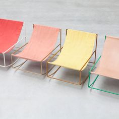 four different colored chairs sitting next to each other on top of a gray flooring