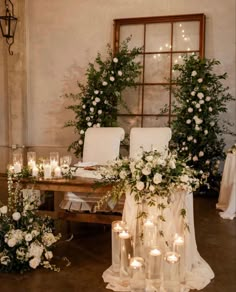 a table topped with lots of white flowers and candles