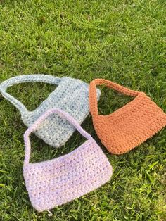 three crocheted purses laying on the grass