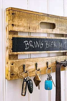 a wooden rack with keys hanging from it's sides and writing on the wall