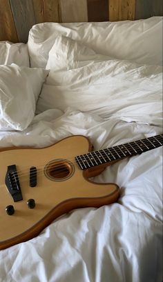 an acoustic guitar laying on top of a bed