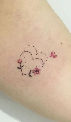 a small heart tattoo with flowers on the side of her arm and an arrow in the shape of a heart