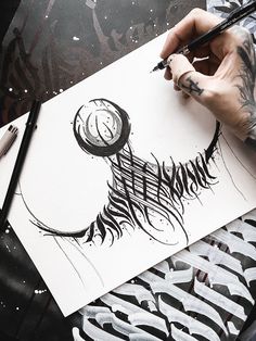 a person is drawing with black ink on white paper