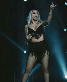 lady in black outfit performing on stage with microphone