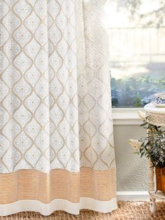 a bathroom with a white shower curtain next to a potted plant on the window sill