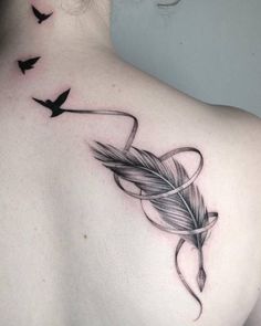 the back of a woman's shoulder with birds flying around it and an arrow tattoo