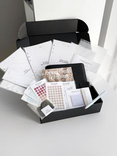 an open black box with papers and other items in it on top of a white table