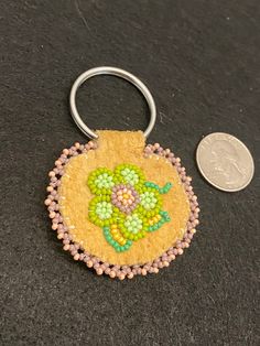 a small keychain with beads on it next to a coin