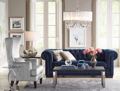 an elegant living room with blue couches and chandelier in the centerpiece