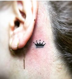 a small crown tattoo on the ear