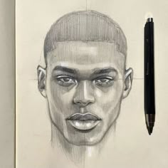 a pencil drawing of a man's face on paper next to a black pen