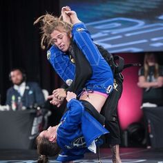 two people in blue and black outfits are doing tricks on stage with one person upside down