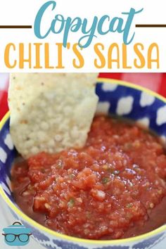 a bowl filled with salsa and tortilla chips on top of a red table cloth