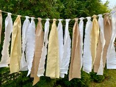 some white and yellow ribbons hanging from a line in front of green grass with trees