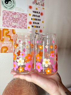 two pink and orange flowers painted on the inside of wine glasses, one being held by a woman's hand