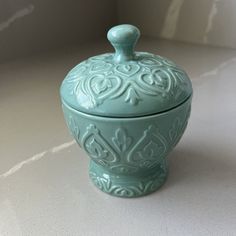 a blue ceramic covered jar sitting on top of a white counter next to a wall