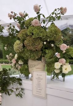 a vase filled with lots of flowers sitting on top of a white table covered in greenery