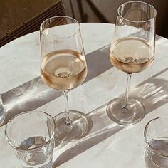 three wine glasses sitting on top of a white table