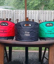 three cooler bags sitting on top of a wooden table next to a white picket fence